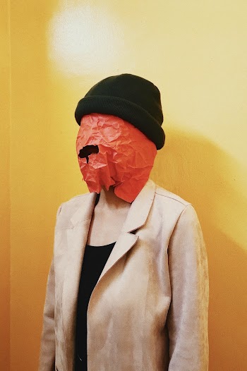 Woman Covered With Paper on the Head standing Beside Yellow Wall