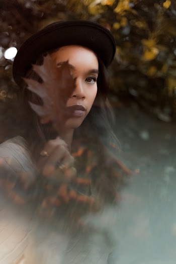Woman Covering Face With Brown Leaf