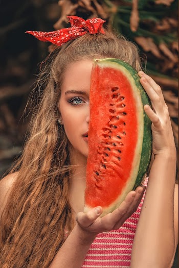 Woman Covering Half of Her Face With Sliced Watermelon