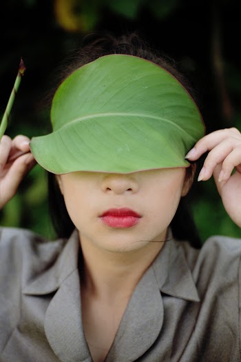 Woman Covering Her Eyes With a Leaf