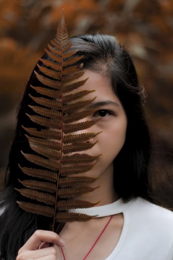 Woman Covering Her Face With Boston Fern Leaf