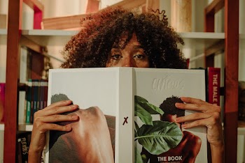 Woman Covering Her Face With White and Green Book