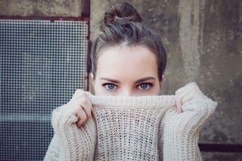 woman covering her lip with sweater