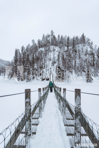 Woman crossing a suspension bridge in a snowy Oulanka National Park, Finland