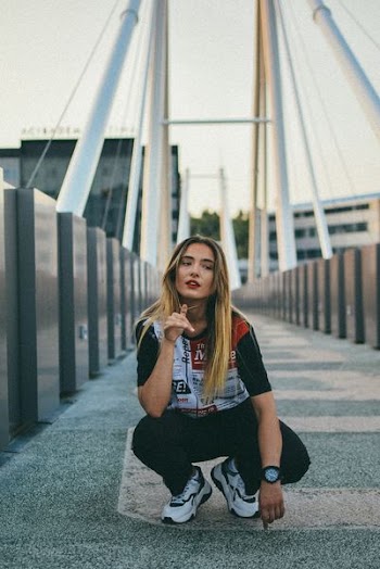 woman crouching on bridge at daytime