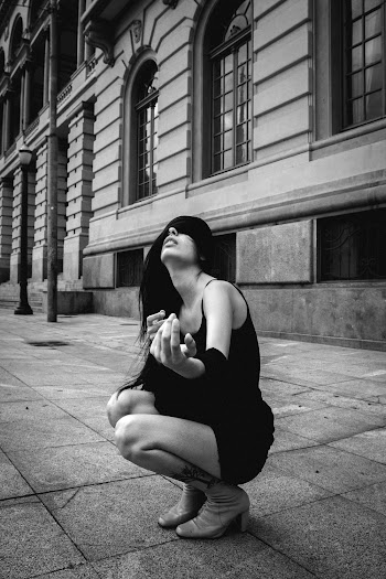 Woman Crouching on Pavement Near Building