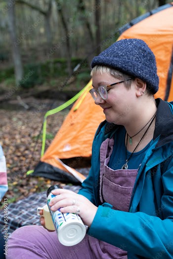 Woman drinking from insulated drink container while camping