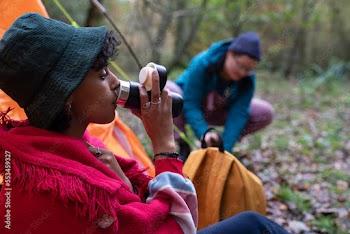 Woman drinking from insulated drink container while camping