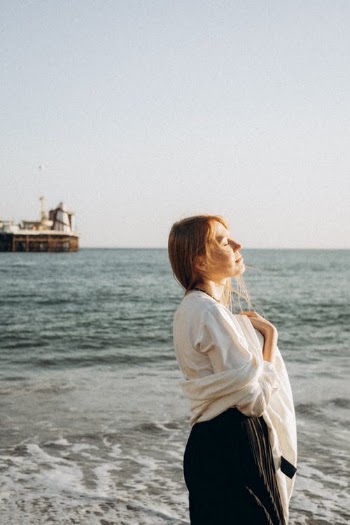 Woman Facing the Sun with Eyes Closed on a Beach · Free Stock Photo