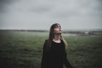 woman facing upward standing on green grass