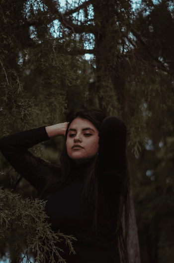 Woman Fixing Her Hair Near Pine Tree