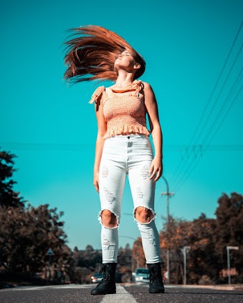 Woman Flipping Her Hair While Standing in the Middle of Road