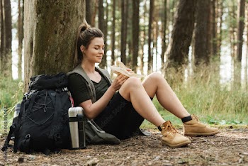Woman hiker during small halt eating sandwich in green forest