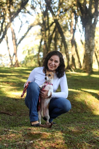 Woman holding a brown and white dog while crouching  