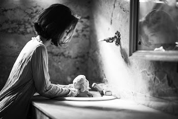 Woman Holding a  Doll In a Sink