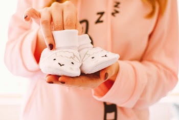 Woman Holding Baby's Pair of White Shoes