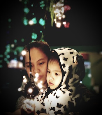 Woman Holding Baby Looking At String Lights