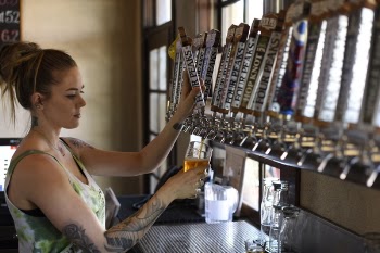 Woman Holding Beer Tap Handle and Pilsner Mug
