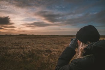 woman holding binoculars seeing far on field