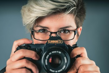 Woman Holding Black Canon Camera at Face Level