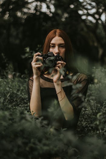 Woman Holding Black Dslr Camera Surrounded by Plants