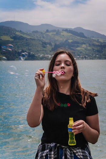 Woman Holding Bottle While Blowing Bubbles