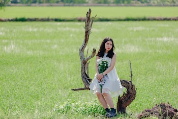 Woman Holding Bouquet of White Flower Sitting on Drift Wood