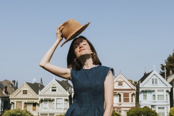 Woman Holding Brown Hat Near Houses