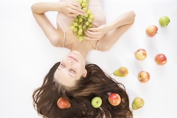 Woman Holding Bunch of Grapes Beside Apples and Pears on Floor Closeup Photography