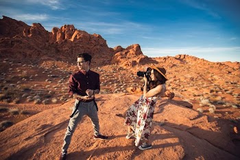 woman holding camera while taking photo on mountain