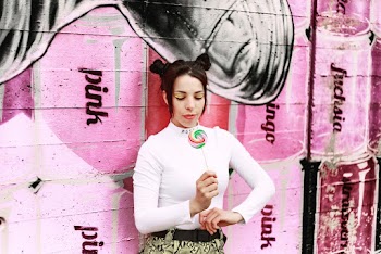 Woman Holding Candy Against Pink Wall