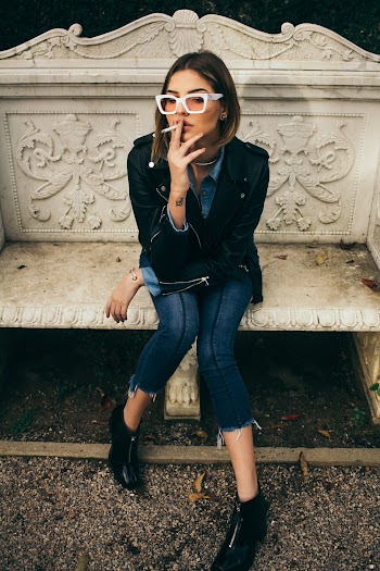 Woman Holding Cigarette Sitting on Concrete Bench