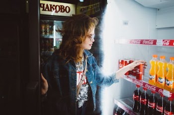 woman holding Coca Cola can near royal soda bottle