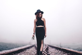 woman holding flowers looking on train rails