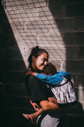 Woman Holding Girl Beside Gray Wall