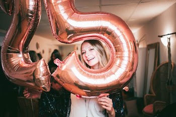 woman holding gold 25 figure balloons