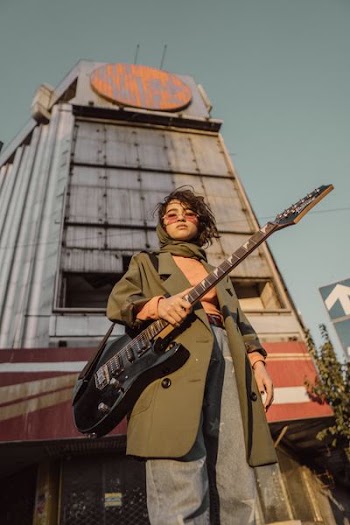 woman holding guitar near building