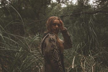 Woman Holding Hair While Standing on Grass Field