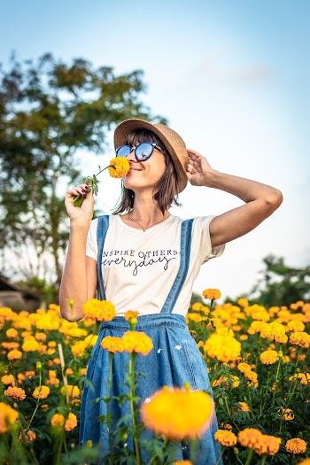 Woman Holding Hat And Smelling Yellow Flower