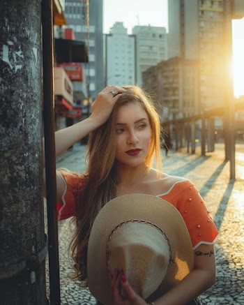 Woman Holding Hat Beside Post Near Buildings