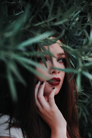 Woman Holding Her Cheek Under Green Leaves