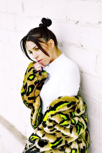 Woman Holding Her Chin While Leaning on White Wall
