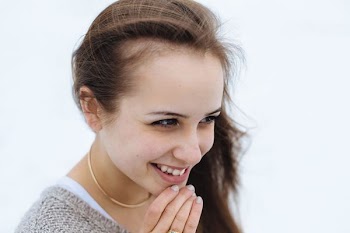 woman holding her chin while smiling