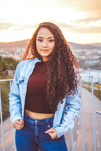 Woman Holding Her Denim Jacket While Standing Near Rail