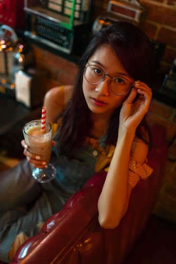 Woman Holding her Eyeglasses While Holding Glass of Shake