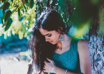 woman holding her hair standing near tree branch