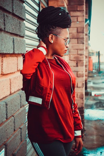 Woman Holding Her Neck While Standing Beside Wall