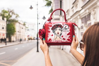 Woman Holding Her Red and White Leather Handbag Up High at the Sidewalk