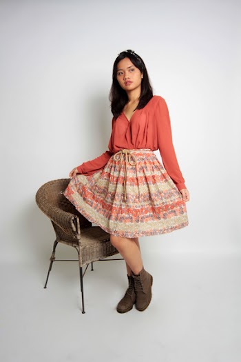 Woman Holding Her Skirt Standing Beside Wicker Armchair