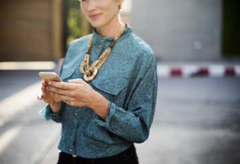 Woman Holding Iphone Wearing Long-sleeved Shirt And Gold Necklace